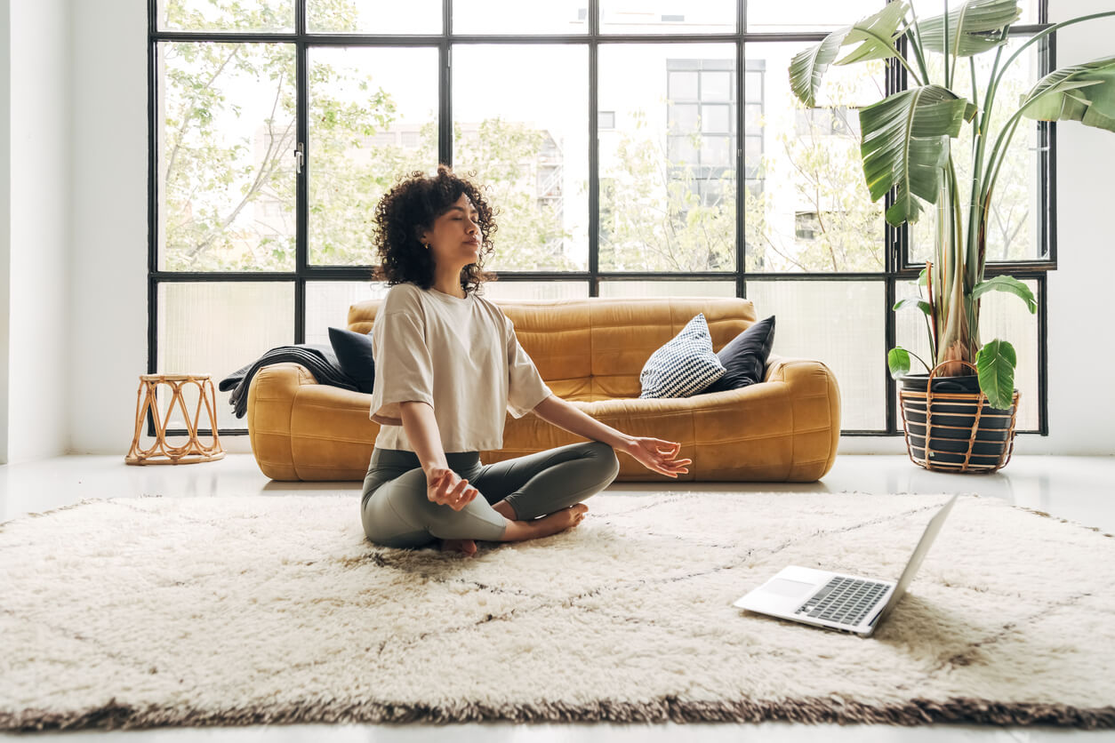 Woman meditating for work life balance in front her laptop.