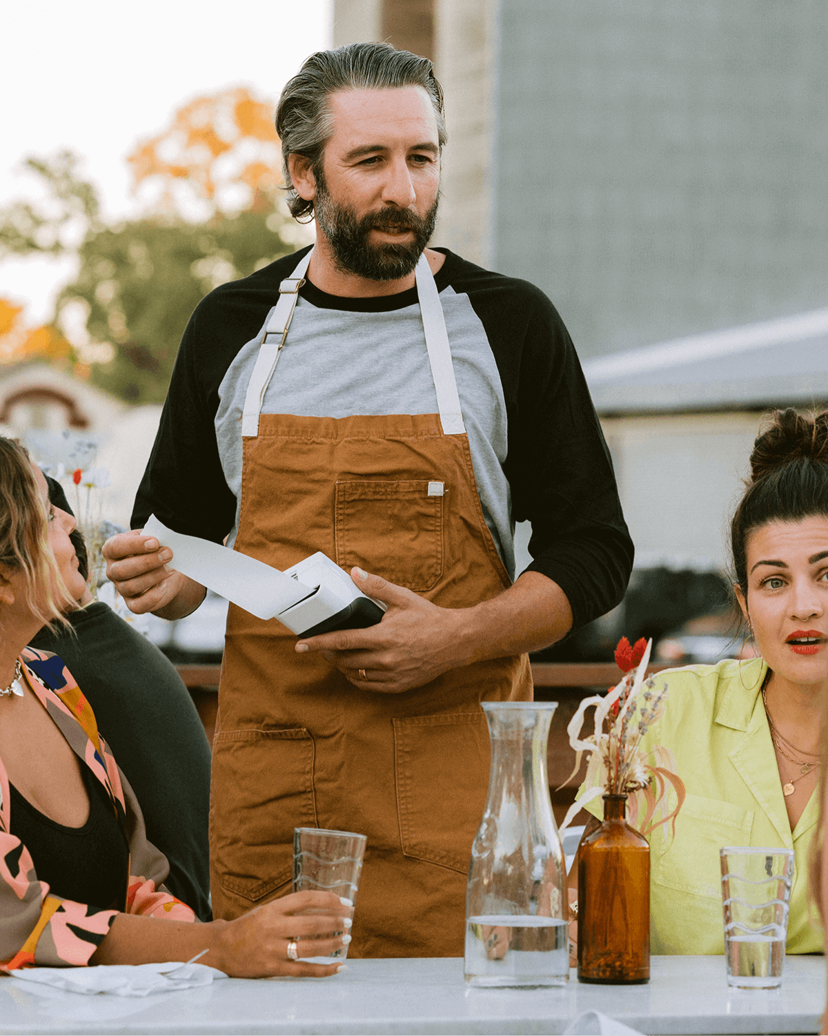 Server handing out a receipt to people sitting at a table using the Clover Flex Smart Terminal